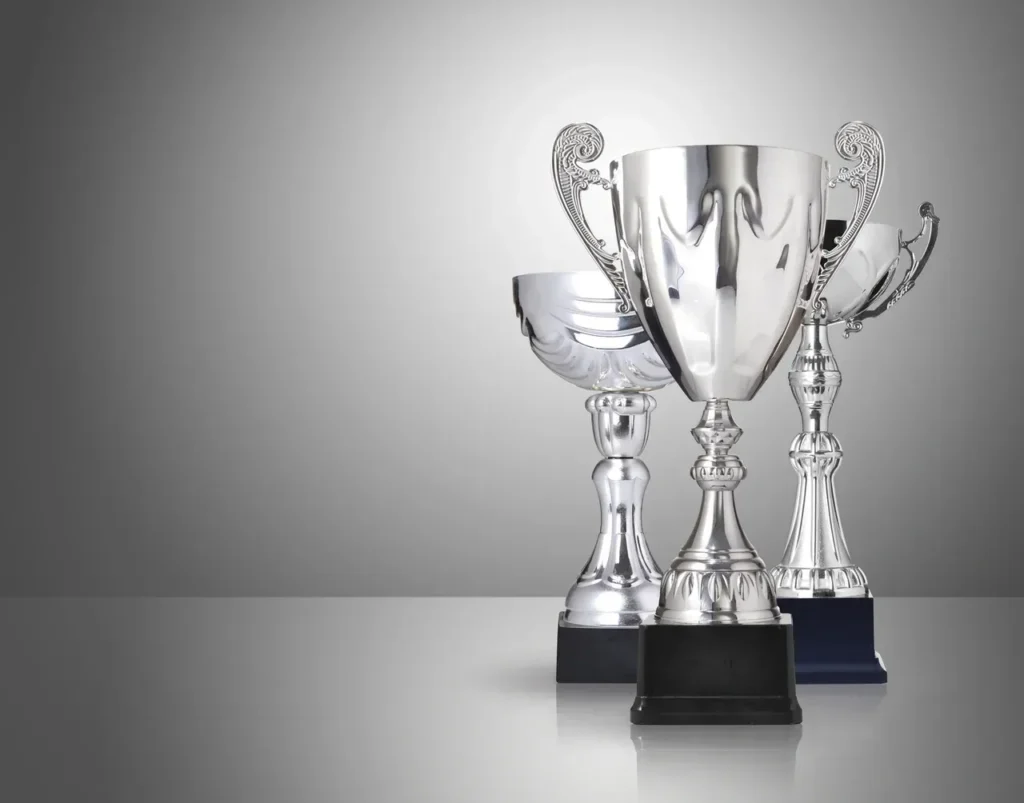 Three silver trophy cups on a neutral grey background