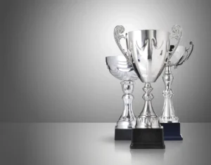 Three silver trophy cups on a neutral grey background
